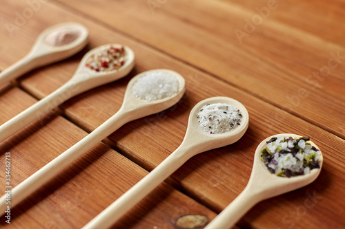 food, culinary and unhealthy eating concept - spoons with salt and spices on wooden table