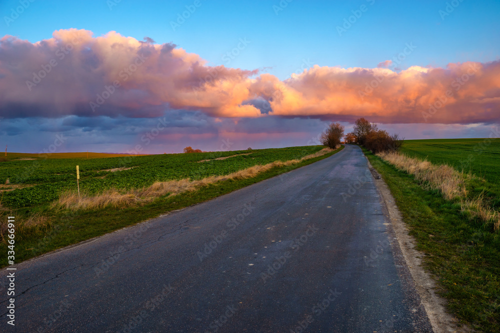 Beautiful, colorful clouds after the storm over the asphalt road