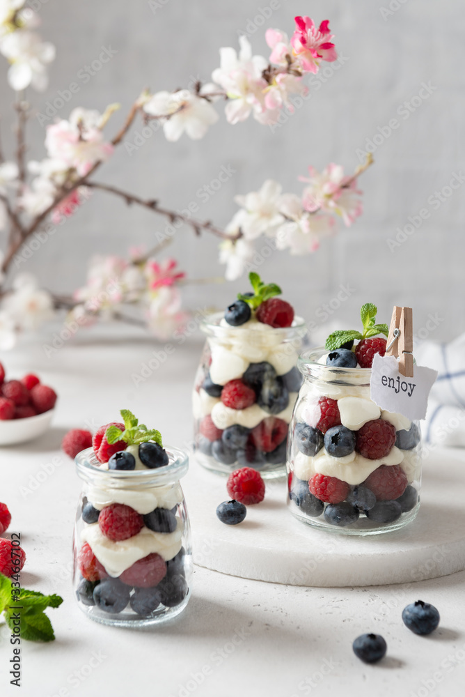Healthy blueberry and raspberry parfait in mason jars on a white concrete background. Summer, spring dessert. Side view. Recipe, menu Healthy blueberry and raspberry parfait in mason jars on a white concrete background. Summer, spring dessert. Side view. Recipe, menu