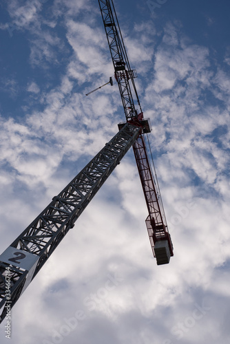 High-rise construction crane with a long arrow on a blue sky background. Industrial concept.