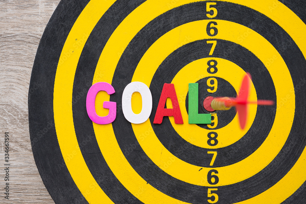 Color alphabets GOAL on dartboard background with red arrow hit center of target. Business, management and marketing concept. Business goal and objectives is a part of the planning process.