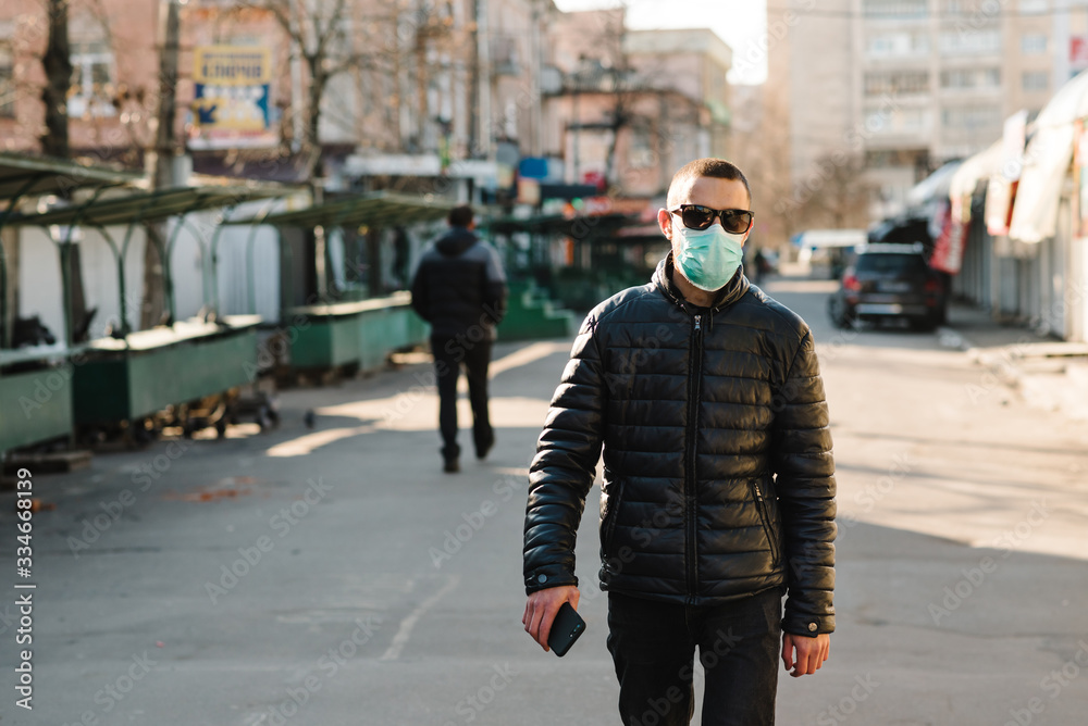 Fototapeta premium Coronavirus. Man wearing medical protective mask walking on street. Corona virus COVID-19. Air pollution, virus, Chinese pandemic concept. Virus, pandemic, panic concept.