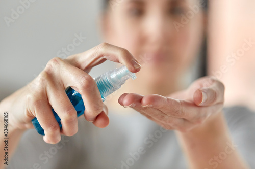 hygiene  health care and safety concept - close up of woman spraying antibacterial hand sanitizer