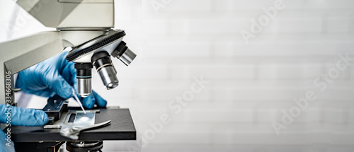 doctor wearing protective gloves using microscope researching corona virus microscopic cells testing vaccination cure, medical center lab china Wuhan world health organization research facilities photo