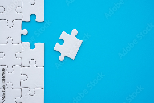 Fototapeta Naklejka Na Ścianę i Meble -  The last piece of jigsaw puzzle to complete task on blue background. Business strategy teamwork, problem solving concept. Teamwork is collaborative effort of team to achieve goal or complete mission.
