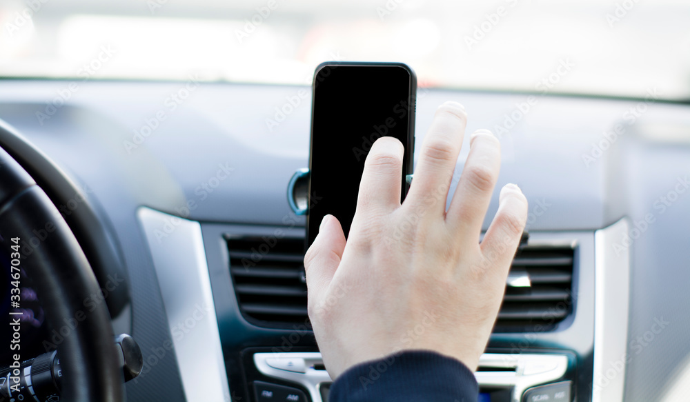 A man's hand driving on the Phone is fixed on the dashboard of the car with a black background for inserting text, images. front seat type