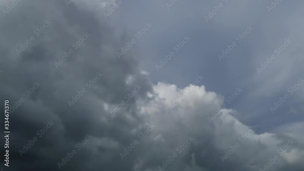 Dramatic rain clouds on dark sky background before thunder storm. Puffy fluffy white & grey clouds in dramatic fast moving motion on beautiful horizon blue sky with sunlight & sun rays, TimeLapse Dramatic rain clouds on dark sky background before thunder storm. Puffy fluffy white & grey clouds in dramatic fast moving motion on beautiful horizon blue sky with sunlight & sun rays, TimeLapse
