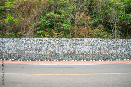 Gabion protection wall, rock stone In steel wire mesh against falling rock from mountain into road.