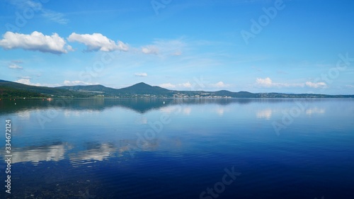 Panorama of Lake Bracciano in Roma of Italy under blue sky. White clouds and mountains reflecting on the lake