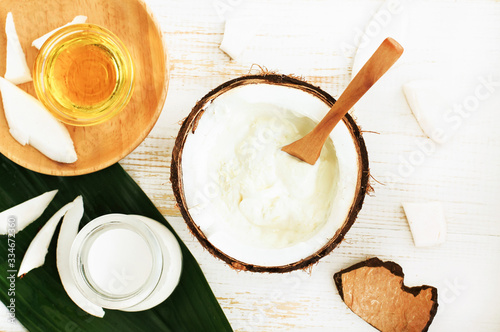 Making coconut oil cosmetic treatment, skincare scrub, body butter, hair therapy oil. Nut with coconut meat milk, containers with organic oil, ingredients top view.