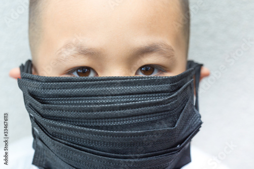 PM2.5 Coronavirus and air pollution concept. Little asian boy wearing a lot of black mask for protect pm2.5 and looking to camera. Wuhan coronavirus and epidemic virus symptoms.