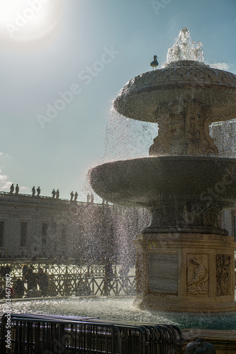 Zabytki na placu Św. Piotra. Na pierwszym planie ogromna fontanna, a w oddali widać bazylikę świętego Piotra, Włochy.