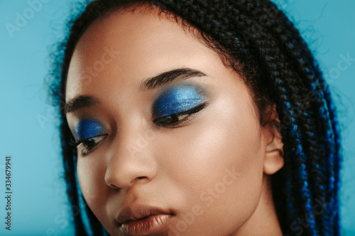 Photography Close up of african model with stylish metal blue eyeshadows makeup look down