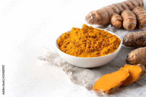 Fototapeta Naklejka Na Ścianę i Meble -  Curcuma powder in bowl and fresh turmeric root on white . Healthy spice immunity. Close up. Natural antiseptic.