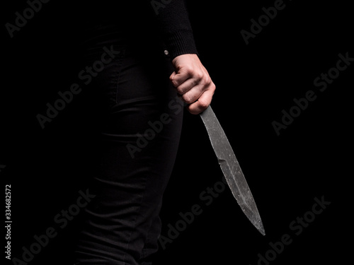 Girl holding in hand steel throwing knife on black background (ID: 334682572)