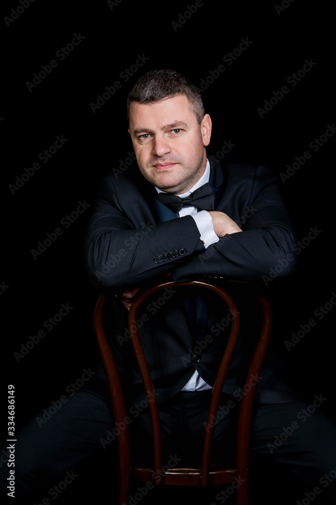 beautiful businessman wearing black suit sitting on black studio background beautiful businessman wearing black suit sitting on black studio background