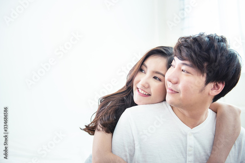 Happy young man and woman hugging embracing indoors. Portrait close up smiling husband and wife piggyback ride at apartment and looking out.