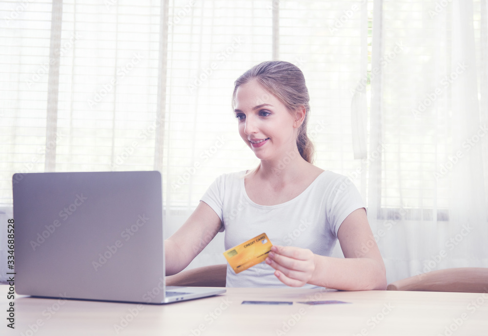 Obraz premium Caucasian young woman holding credit card with Laptop for online shopping or pay public utility bill via digital application, smart life with stay at home and social distancing concept.