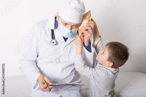 Boy  gives a big shell to doctor. Portrait of smart pediatrician with little patient in clinic office. Joyful kid smiling and performing approving gesture. Medicine and healthcare concept photo