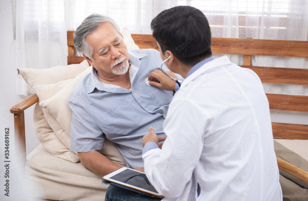Obraz premium Caucasian doctor use laptop and talk with old asian male patient about disease symptom, elderly health check up at home.