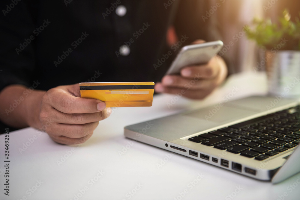 Male businessmen use credit cards to conduct financial transactions through phones, tablet, and laptop in the morning. Male businessmen use credit cards to conduct financial transactions through phones, tablet, and laptop in the morning.