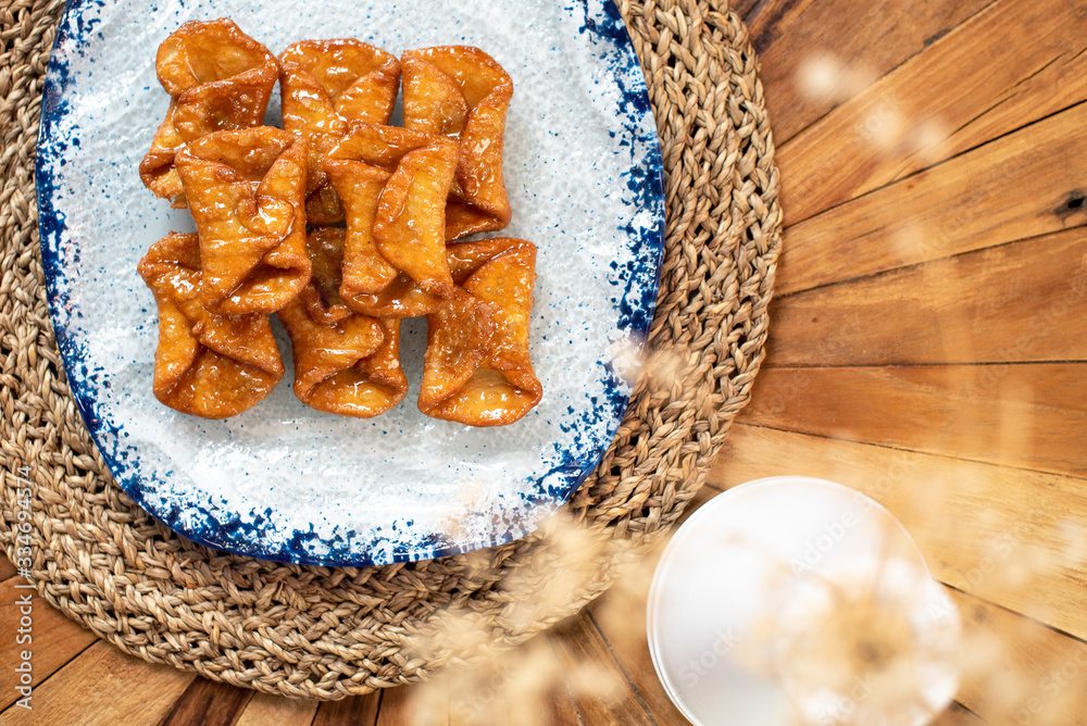 Fototapeta premium Top view of typical sweets of Spanish gastronomy on rustic wooden table and polka dot plate (Pestiños)