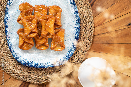  Top view of typical sweets of Spanish gastronomy on rustic wooden table and polka dot plate (Pestiños) photo