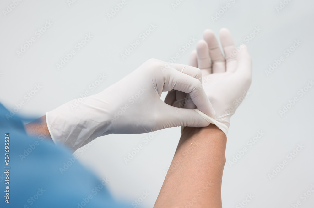 Woman doctor putting blue latex medical gloves on white background.Surgeon wearing gloves before surgery at operating room.Risk and infection control concept. Woman doctor putting blue latex medical gloves on white background.Surgeon wearing gloves before surgery at operating room.Risk and infection control concept.