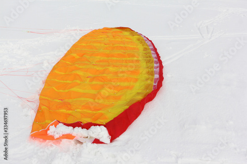 Orange kite lying on the snow