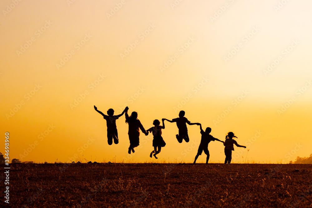 Silhouette group of happy children jumping playing on mountain at sunset, summer time Silhouette group of happy children jumping playing on mountain at sunset, summer time