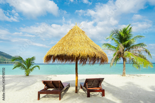 Vacation in tropical countries. Beach chairs, umbrella and palms on the beach. © upslim