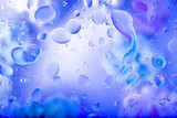 Mixing oil and water drops on a glass. Abstract macro colorful background