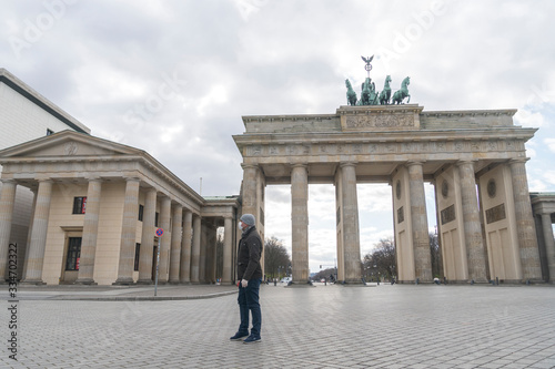Tourist wearing medical protective mask and gloves posing alone in front of the Brandenburg Gate during the city's lockdown