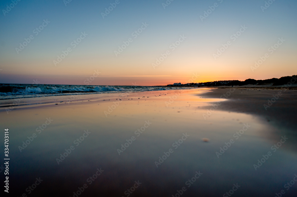 sunset on a beach in huelva in summer. The sun is reflected on the seashore
