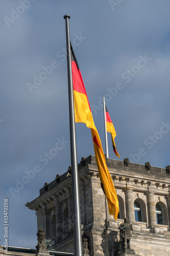 German flag fluttering against cloudy sky on the top of the tower in Berlin Bundestag Reichstag or Bundestag, seat of the German Parliament