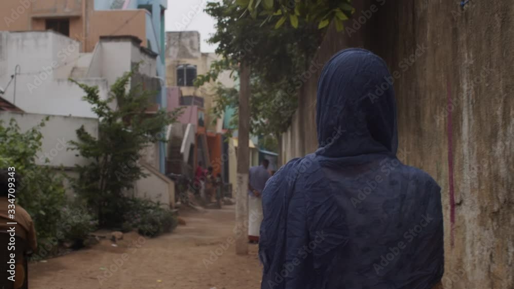 Back view of Indian woman in blue shawl going on narrow city street slow motion. Unrecognizable authentic girl walking on urban background in India. Real people snapshot asian lifestyle
