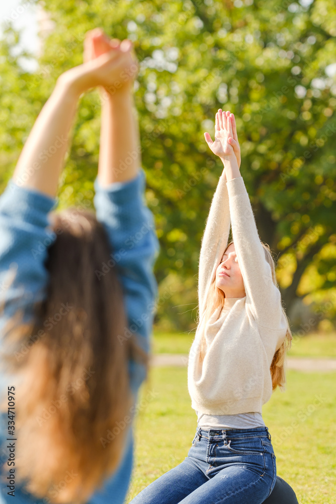 Obraz premium A group of young people meditate outdoors in a park. 