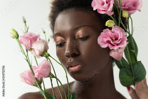 tender naked african american girl with pink flowers isolated on white