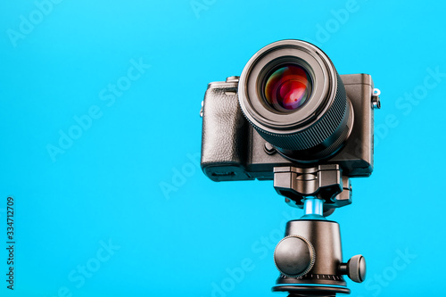Professional camera on a tripod, on a blue background. Record videos and photos for your blog or report.