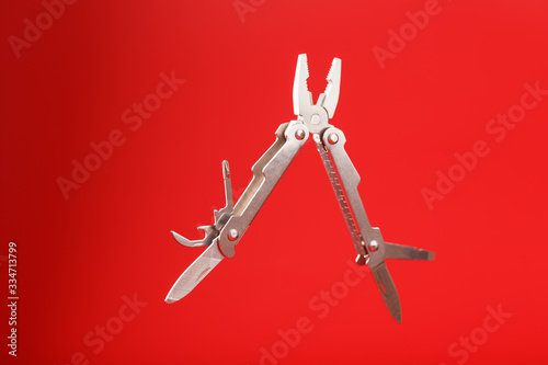 Multitool is a multi-functional tool on a red background. The concept of an open, flying multi-tool with free space. photo