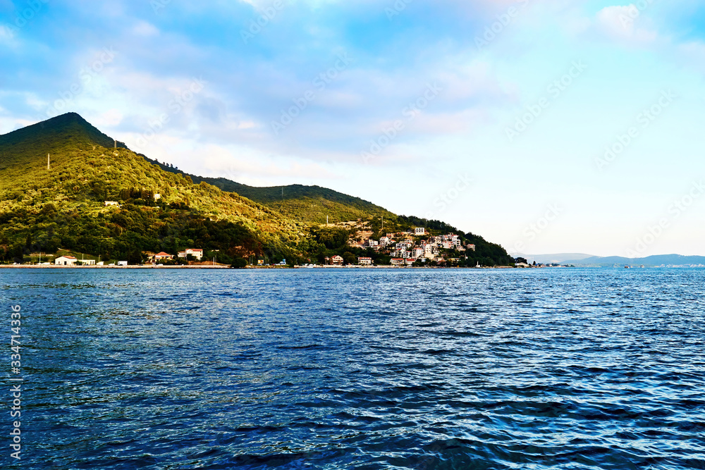 Lonely island with a village on the shore in the middle of the endless blue sea Lonely island with a village on the shore in the middle of the endless blue sea