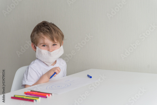 Little boy in medical mask sitting on the chair and smiling