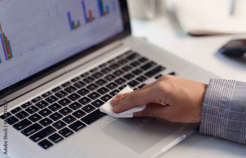 Worker disinfects and cleans the laptop and keyboard with antibacterial wet wipes to protect against corona virus covid-19 during pandemic outbreak. Hygiene and virus prevention at work or at home