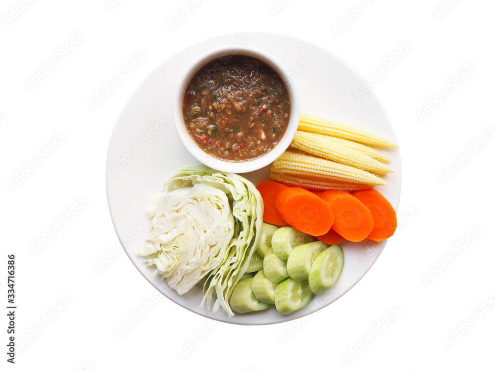 Top view of thai food with chili paste or nam prik ka pi in cup and boiled vegetables with cabbage, cucumber, carrots and baby corn in dish isolated on white background. - obrazy, fototapety, plakaty 