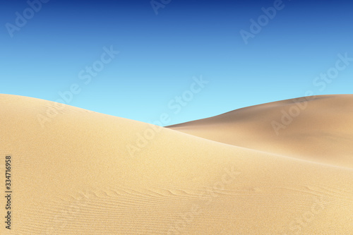 Smooth sand dunes with waves under clear blue sky