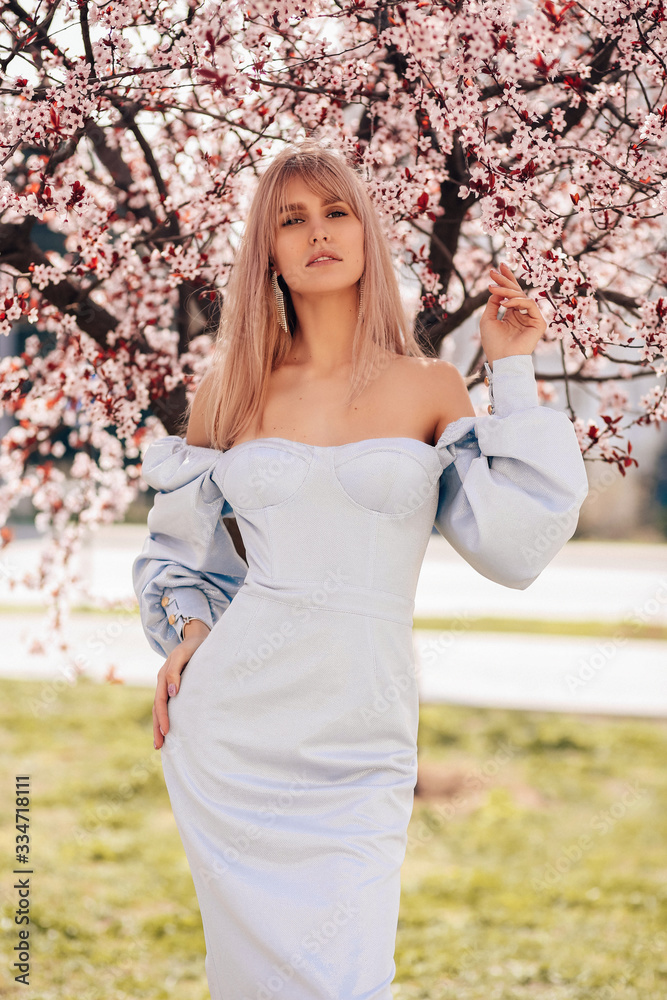 beautiful girl with blond hair in elegant dress posing among blossoming ...