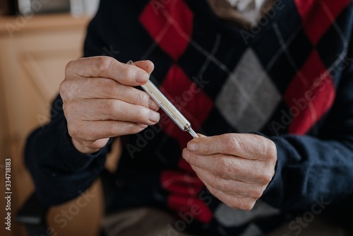 Senior Elderly Man Holding thermometer in Hands.