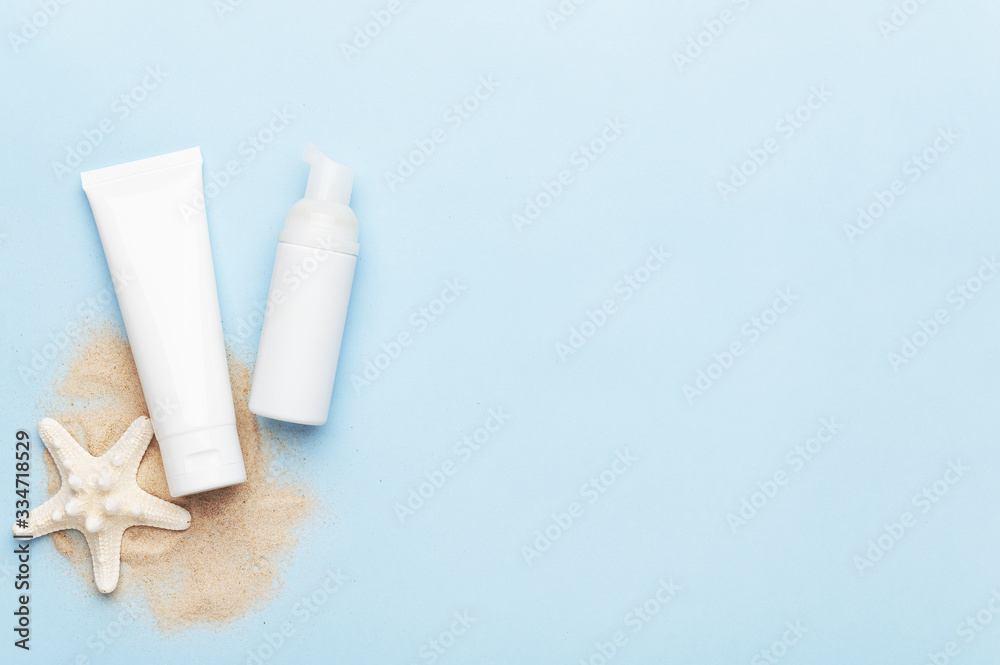 Flacon with soft foam and hand cream with blank unbranded mockup. Copy space in right side. Professional facial products and beauty concept on blue summer background. Sea sand and starfish. Flacon with soft foam and hand cream with blank unbranded mockup. Copy space in right side. Professional facial products and beauty concept on blue summer background. Sea sand and starfish.