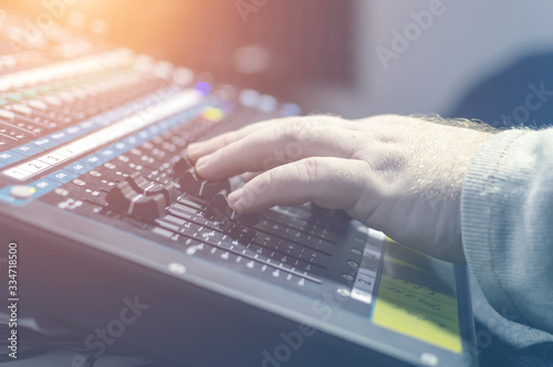 Human hand on the mixing console in the recording Studio. Spotlight.