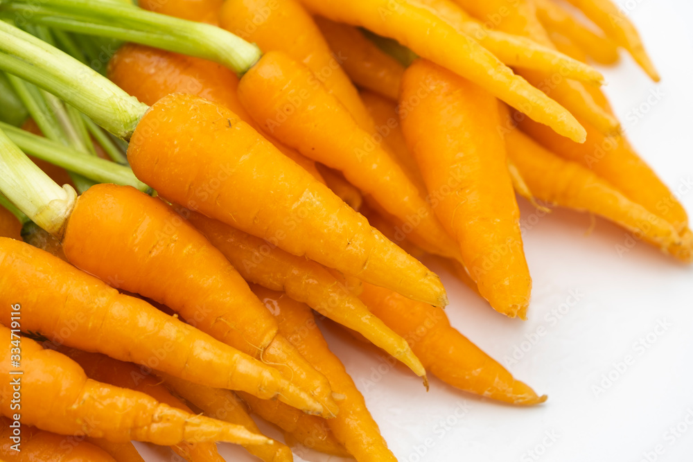 Pile of fresh raw baby carrots with green leaves isolated on white background, vegetable food concept Pile of fresh raw baby carrots with green leaves isolated on white background, vegetable food concept